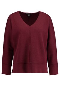 Burgundy striktrøje med V-hals, lange ærmer og en søm foran. Har sideslids og en afslappet pasform.