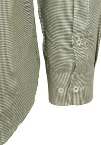 Close-up van een groen-wit houndstooth-gepatenteerde mouw en manchet met twee knopen, waarbij de stofstructuur en stikseldetails zichtbaar zijn.