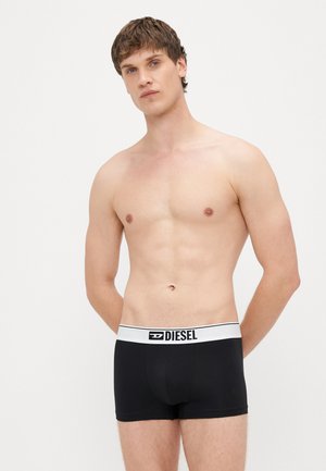 Μαύρα ανδρικά εσώρουχα boxer με λευκή ζώνη μέσης που φέρει το λογότυπο "DIESEL". Λείο ύφασμα, εφαρμοστή σχεδίαση και μήκος μέχρι το μέσο του μηρού.
