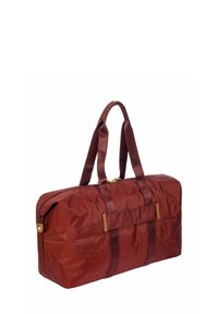 Sac de sport en nylon bordeaux avec deux poignées en tissu et fermeture éclair dorée. Dispose d'une base plate et d'une surface lisse et texturée, avec des bandes d'accentuation.