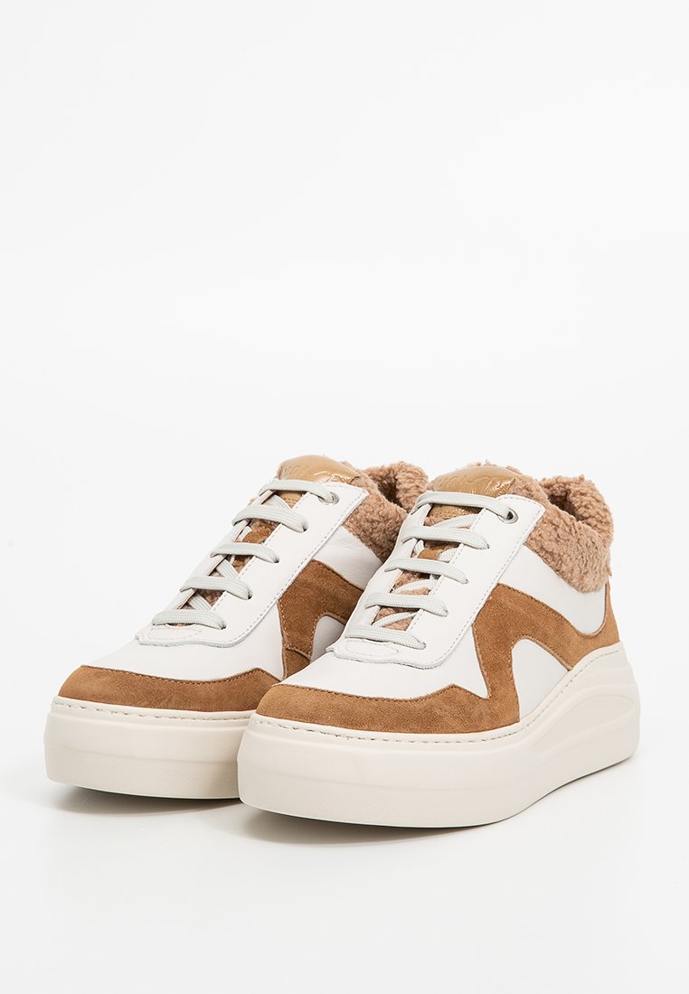 Weiße und beige Sneakers mit Wildleder- und Fellakzenten, Schnürverschluss, dicker Sohle und geschwungener Form. Strukturierte Oberfläche und kontrastierende Farben.