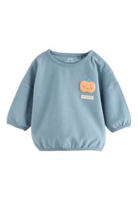 Blue long-sleeve baby shirt with elastic hem and a small orange smiling pumpkin patch with a blue stem on the chest.