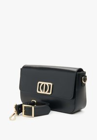 Černá kožená křížová taška s klopou v zlaté barvě, obdélníkový tvar, odnímatelný popruh a hladká textura. Design s překlápěcí klopou.