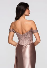 Robe de soirée à épaules dénudées dans une nuance douce de rose. Présente un travail de perlage délicat et une broderie florale sur un tissu semblable au satin. Silhouette lisse et ajustée.