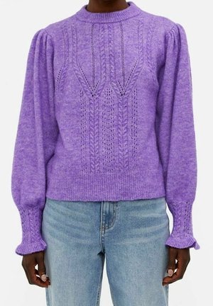 Pull en maille violet avec un col rond, des manches bouffantes et des motifs texturés. Fini avec des bords-côtes aux manchons et à l'ourlet, associé à un jean clair.
