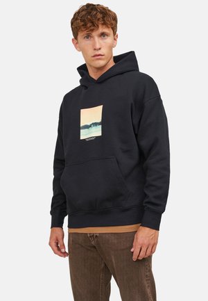 Schwarzer Baumwoll-Hoodie mit einer Fronttasche, die ein rechteckiges Grafikdesign einer Landschaft in sanften Farben zeigt. Mit gerippten Bündchen und Saum.