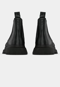 Botas de pele pretas até ao tornozelo com painéis laterais elásticos, sola de borracha robusta e costura em contraste nas laterais. Textura suave, design minimalista.