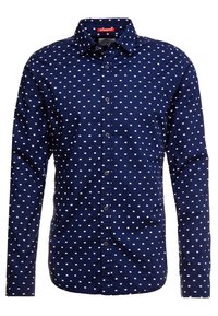 Chemise bleu marine à boutons avec un motif carré blanc répété, manches longues et col classique. Fabriquée dans un tissu lisse avec un léger éclat.