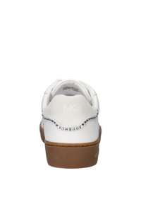 Zapatilla blanca con parte trasera de ante, equipada con tachuelas plateadas en el talón, suela de goma marrón clara y logotipo 'MK' en relieve.