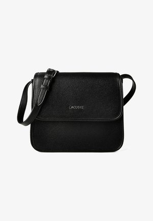 Zwarte crossbodytas van getextureerd leer met verstelbare riem en klepsluiting, voorzien van een klein zilverkleurig Lacoste-logo in het midden aan de voorkant.