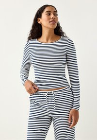 Set med långärmad topp och byxor med horisontella marinblå och vita ränder, utrustad med rund halsringning och dragsko i midjan. Mjukt, ribbat tyg.