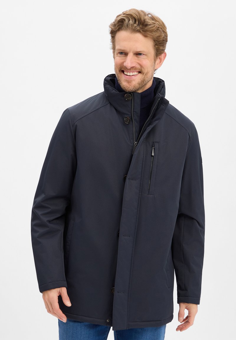 Granatowa wodoodporna kurtka z wysokim kołnierzem, zapięcie na guziki z przodu oraz kieszenią na zamek na klatce piersiowej. Gładka faktura, casualowy styl i długość do połowy.