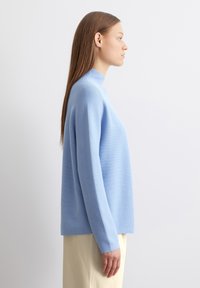 Helles blaues, geripptes Rollkragensweatshirt mit langen Ärmeln, lockerer Passform und glatter Textur, kombiniert mit einem crèmefarbenen Rock.