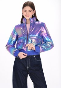 Iridescencyjna krótka kurtka puchowa w kolorze fioletowym i niebieskim z lekko stojącym kołnierzem, z przodu na zamek i dwoma kieszeniami na piersiach. Niebieskie ściągacze na mankietach i u dołu.