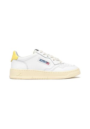 Sneaker in pelle bianca con punta traforata, suola beige, linguetta sul tallone gialla e logo del marchio blu sul lato. Chiusura frontale con lacci neutri.