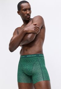 Boxer shorts verdi con motivo, caratterizzati da un design testurizzato e dotati di un elastico con marchio. Realizzati in un materiale comodo e elastico.