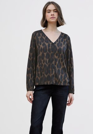 Brun leopardprintbluse med V-udskæring, knapper foran og lange ærmer. Fremstillet af et glat, let stof. Kombineret med mørke jeans.