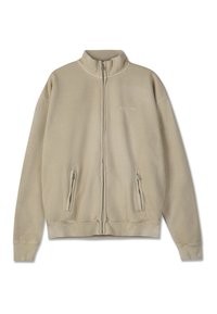 Bežs ar rāvējslēdzēju krekls, kas izgatavots no mīksta auduma ar augstu apkakli, ar divām rāvējslēdzēju priekšējām kabatām un ribotām piedurknēm un apakšmalu.