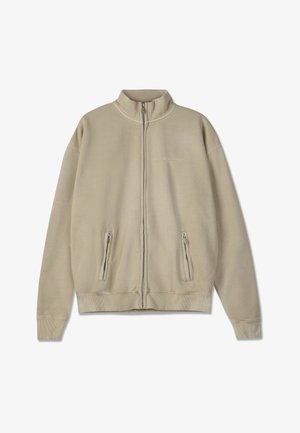 Beżowa bluza z zamkiem, wykonana z miękkiego materiału, z wysokim kołnierzem, posiadająca dwie zapinane na zamek kieszenie z przodu oraz ściągacze na mankietach i u dołu.