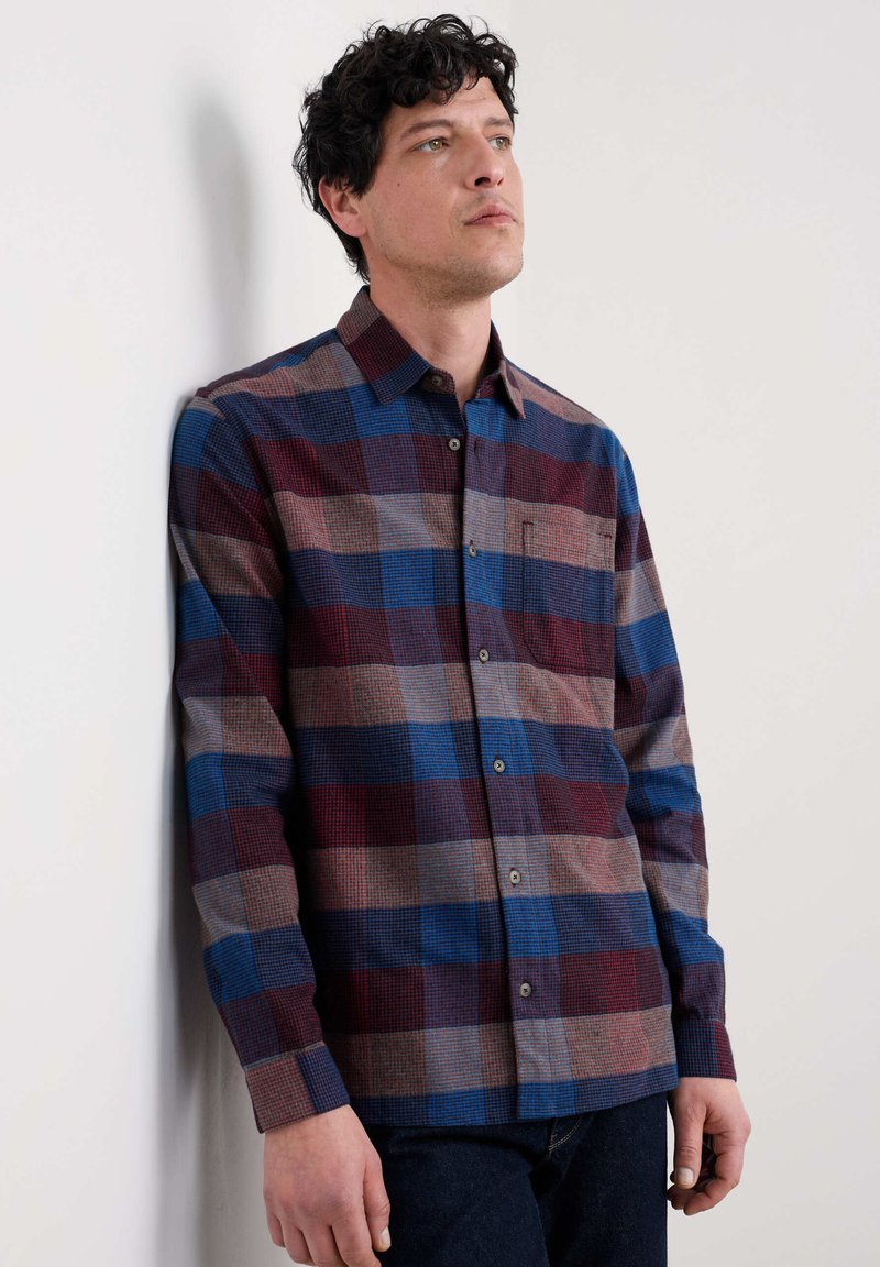 Camicia button-up a scacchi nei colori blu, bordeaux e marrone. Presenta una tasca e un colletto classico. Tessuto testurizzato con una vestibilità strutturata.