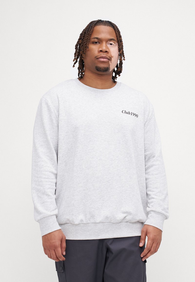 Sudadera gris de cuello redondo con puños y dobladillo acanalados. Presenta "Club1990" impreso en negro. Confeccionada con una suave tela texturizada.