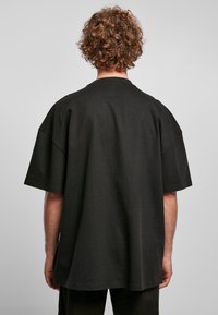 Zwarte oversized t-shirt met korte mouwen, geribbelde textuur, ronde halslijn en een ontspannen pasvorm. Geen zichtbare patronen of accenten.