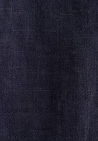 Tissu bleu foncé avec un tissage texturé, présentant une surface lisse et de légères variations de ton. Idéal pour des applications vestimentaires ou de rembourrage.