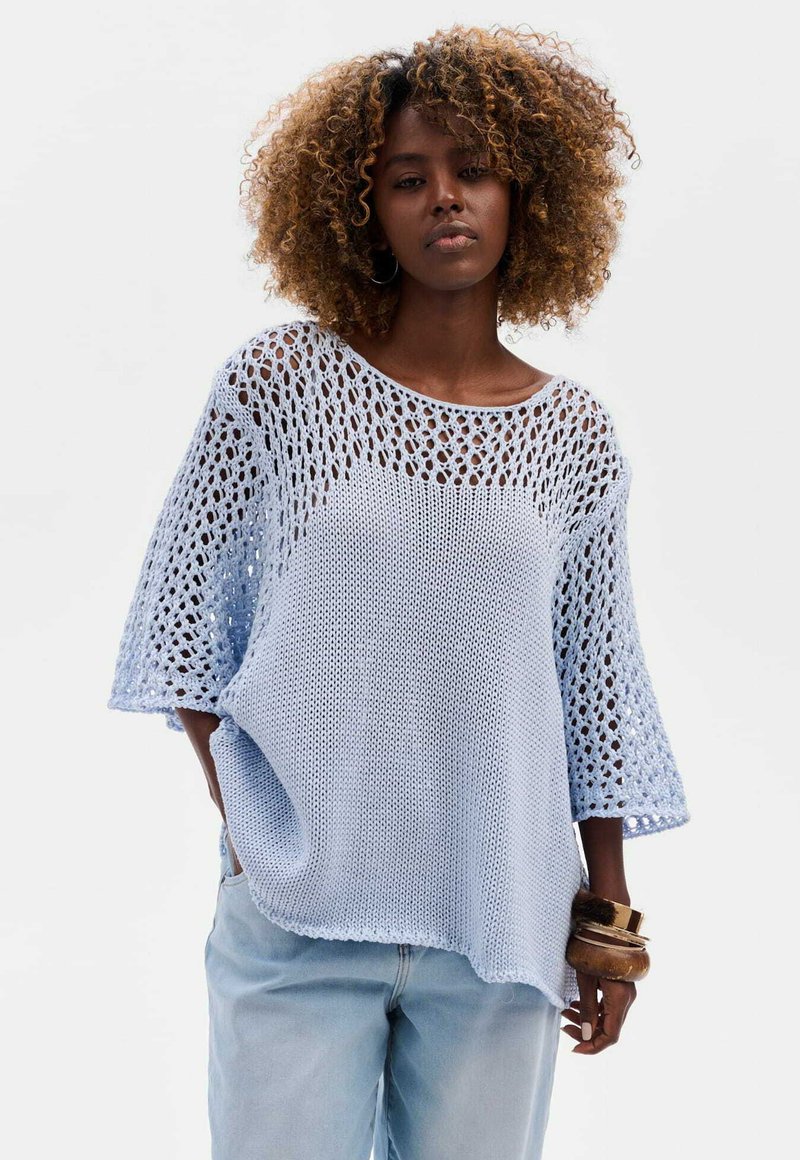 Jasnoniebieski sweter dzianinowy o luźnym kroju, z szerokim dekoltem i krótkimi rękawami z otwartym splotem. Miękka tekstura i swobodny fason.