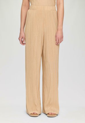 Beige, weite Hosen mit vertikalen Falten, hohem Bund und weichem Textil. Sie haben eine entspannte Passform und enden an den Knöcheln.