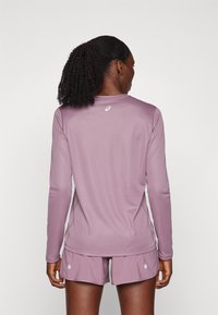 Long-sleeve athletic top in light purple, made of soft, breathable material, paired with matching shorts featuring white accents.