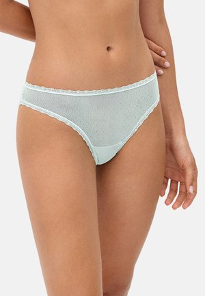 Ropa interior femenina azul claro, semitransparente, con pequeño patrón de puntos y ribete de encaje, usada en las caderas sobre un fondo liso.