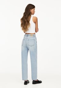 Jeans azzurri chiari a vita alta con un design a gamba dritta, leggere sfumature, due tasche posteriori e un'etichetta beige in vita.