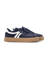 Zapatillas azul marino con franjas blancas. Parte superior de sintético suave, suela de goma, diseño bajo y forma de punta redonda. Cordones en color a juego.