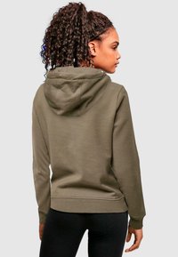 Olivgrön hoodie med justerbar dragsko på huvan, långa ärmar och avslappnad passform, med mjukt tyg och en subtil textur.