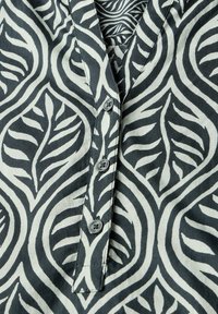 Zwart-wit gestreepte blouse met een bladerenpatroon, knoopsluiting en een zachte, lichte stoftextuur.