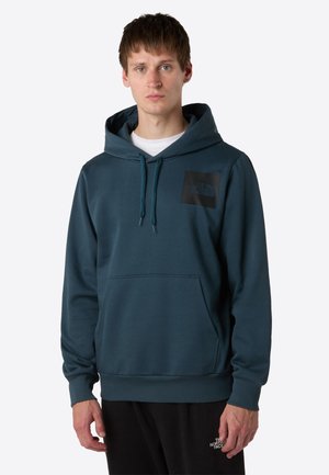 Teal hoodie gemaakt van zachte stof met een voorzak in kangoeroestijl, ribgebreide manchetten en een zwart logo-opdruk op de borst.