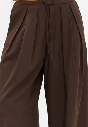 Pantalon plissé marron taille haute avec jambes larges et taille à cordon sur le devant.