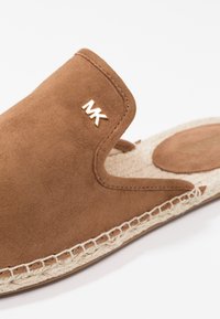Sandale marron en daim à enfiler avec semelle en jute tressée et logo MK doré sur le côté, dotée d’une semelle intérieure rembourrée pour le confort.