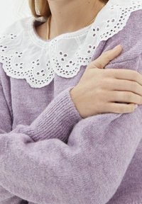 Maglione lavorato a maglia di un leggero viola con un ampio colletto in pizzo bianco, caratterizzato da dettagli ricamati a occhio e polsini a coste.