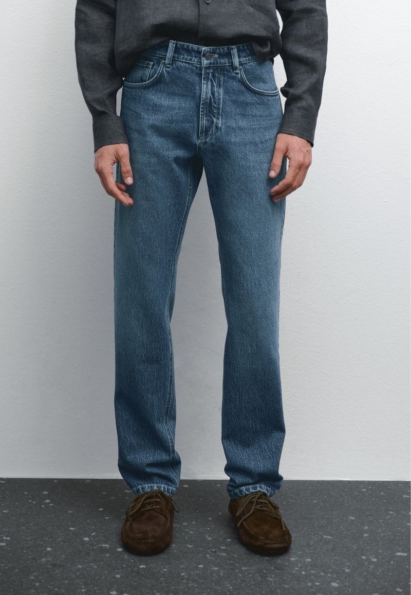 Ljusblåa denimjeans med rak passform, som har fem fickor och knappstängning, bärs med bruna mockaskor.