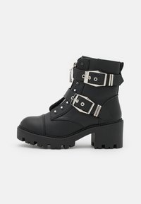 Stivaletti neri alla caviglia realizzati in pelle testurizzata con tacco spesso, dotati di fibbie regolabili in argento e borchie decorative sul davanti.