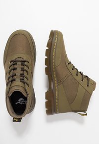 Botas altas marrones con cordones, hechas de un tejido texturizado, con costuras amarillas en suelas translúcidas y con tiradores en el talón, mostradas desde lados superiores y laterales.