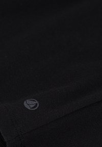 Tessuto nero con una texture liscia. Presenta un piccolo logo sottile in una tonalità più chiara sul bordo. Nessun motivo o accento distintivo visibile.