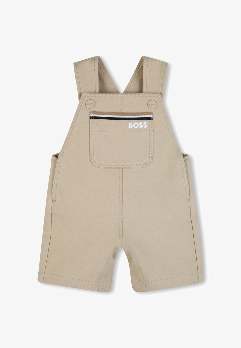 Salopette beige en coton avec bretelles ajustables, poche avant zippée et poches latérales ; détails du logo sur la poche avant.