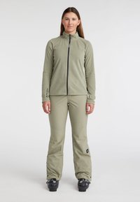 Groene fleecejacket met hoge kraag en ritssluiting, gecombineerd met bijpassende groene waterdichte broek. Beide hebben een gladde textuur en minimale merken.
