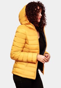 Geel puffer jacket met een capuchon, voorzien van een gewatteerd ontwerp en ritssluiting. Het materiaal lijkt glad en isolerend.
