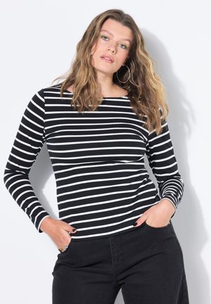 T-shirt à rayures noires et blanches à manches longues avec un col en bateau, offrant une texture douce et un design ajusté, associé à un pantalon foncé.