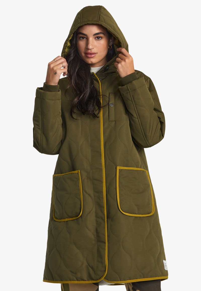 Cappotto trapuntato verde oliva con cappuccio, piping giallo e due tasche frontali. Presenta una chiusura a bottoni e polsini a costine.