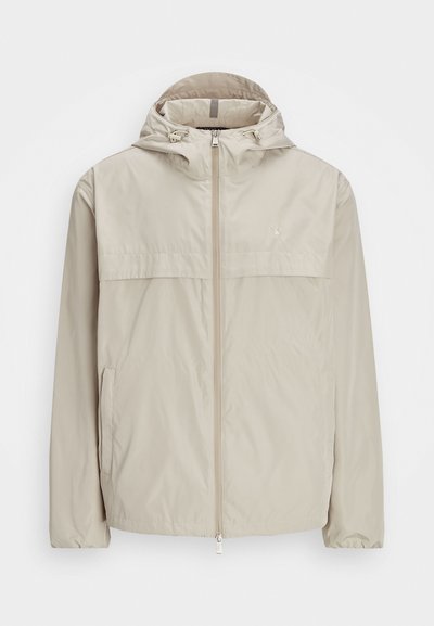 Ανεμολόγιο μπεζ ελαφρύ με κουκούλα, με φερμουάρ μπροστά και ρυθμιζόμενα κορδόνια. Διαθέτει τσέπη στο στήθος και ελαστικούς μανσέτες. Λείος υφασμάτινος.