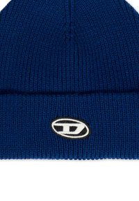 Cappello a berretto blu lavorato a maglia con orlo piegato, caratterizzato da una patch circolare con contorno nero e dettagli bianchi all'interno. Texture morbida.